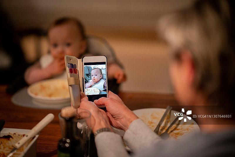 在给一个吃完饭的婴儿拍照图片素材