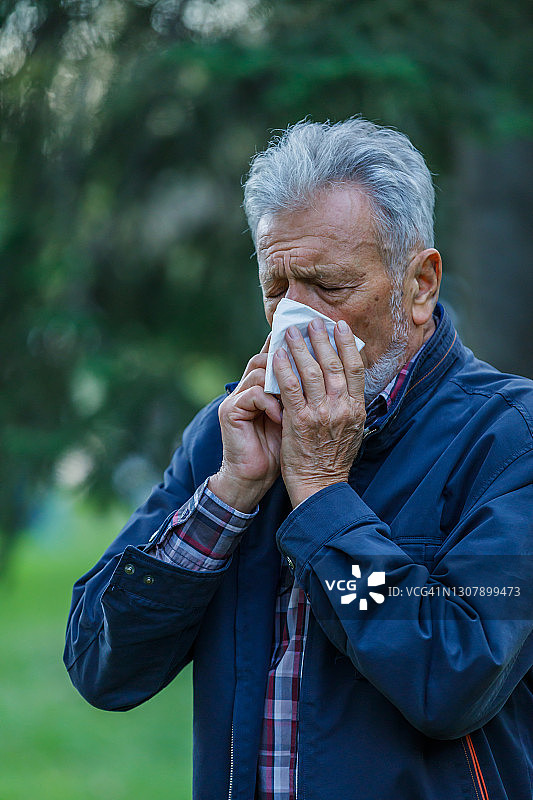 感冒和高烧的生病老人正在室外打喷嚏和咳嗽。图片素材