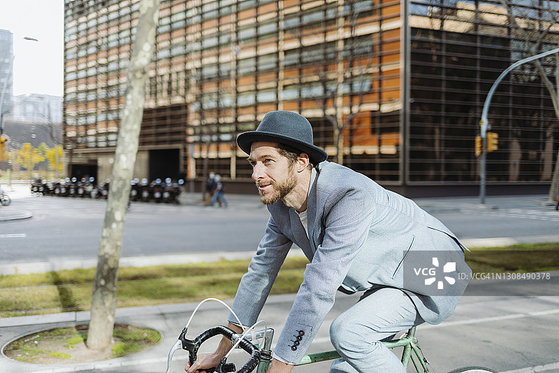 男职业人士戴着帽子骑自行车在城市旅行图片素材