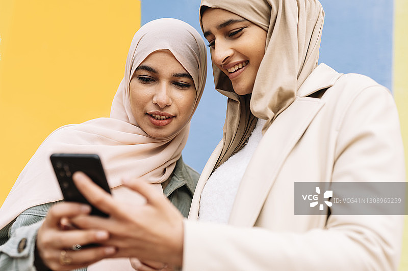 两个阿拉伯女性朋友在户外使用手机。图片素材