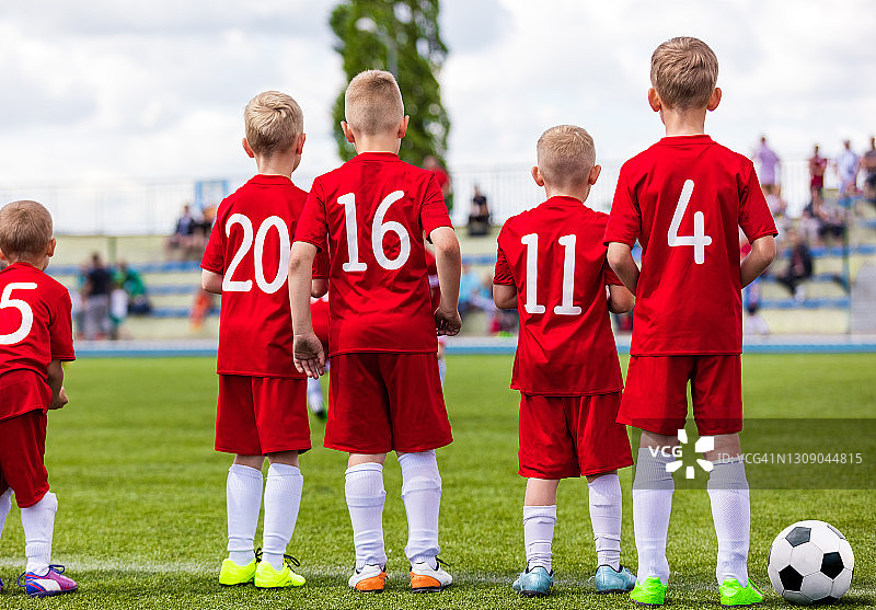 一群男生在足球比赛中站在边线上观看比赛。儿童足球锦标赛图片素材
