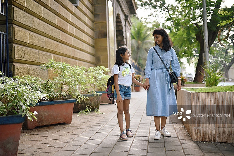 年轻的女孩和她的母亲戴着面具走在城市的街道上图片素材
