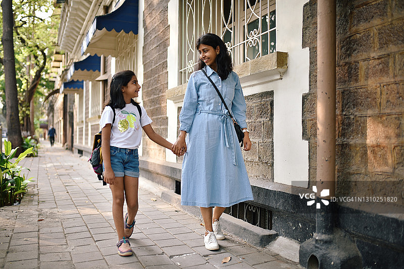 年轻的女孩和她的母亲走在城市的街道上图片素材