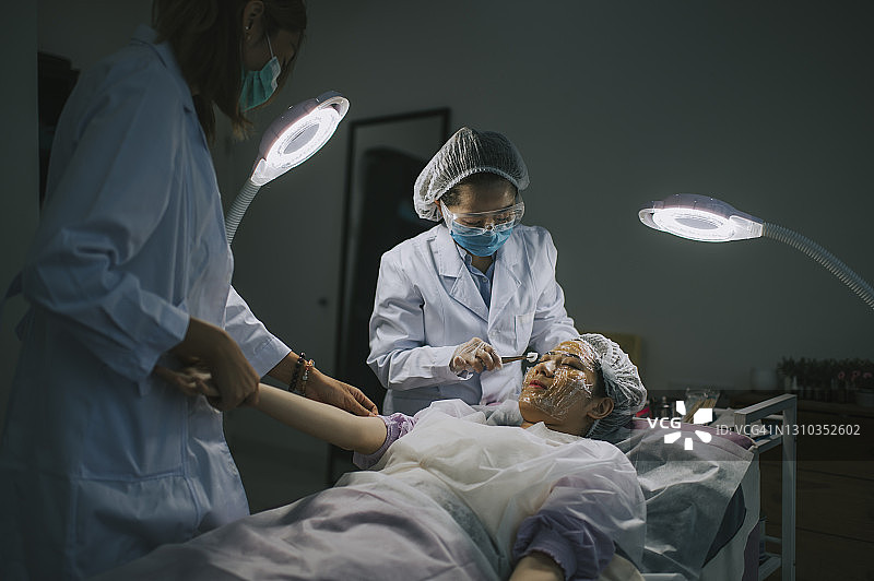 亚洲华人美容师正在应用保湿在病人的脸上，从病人的静脉提取血液从手臂妇女皮肤程序。天然的化妆品。面部护理图片素材