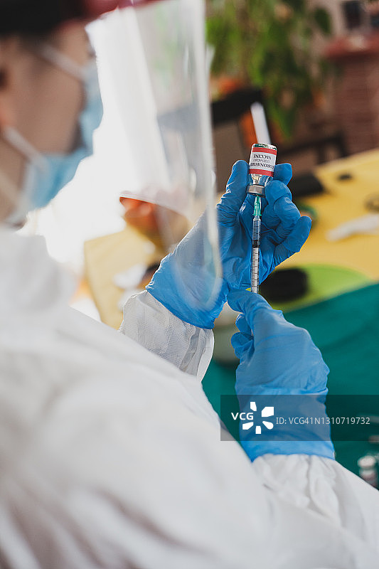 护士手戴手术手套为患者准备COVID-19疫苗图片素材