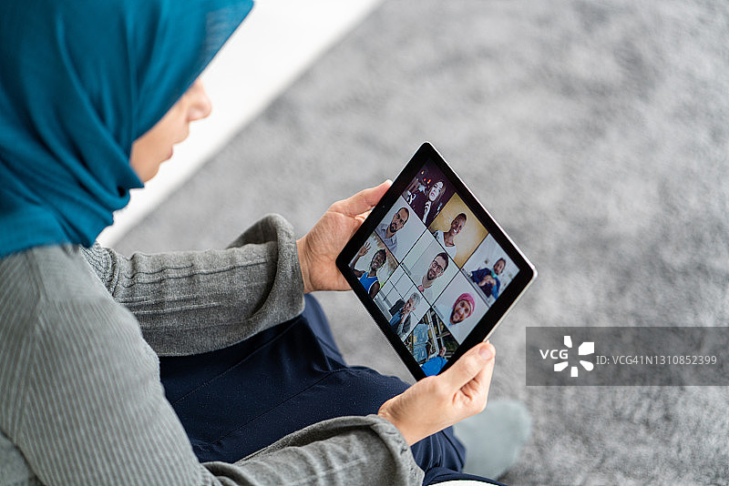 一名穆斯林妇女在平板电脑上聊天和工作图片素材