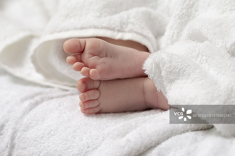 微距特写拍摄的一个四周大的男婴交叉的脚在白色毛巾。水平图像组成图片素材