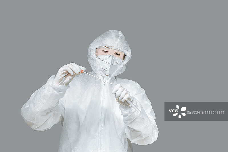 生物学博士戴着呼吸面罩，穿着防护服，拿着一个用于对快速传播的新型冠状病毒covid-19进行涂片的工具包。隔离工作室拷贝空间图片素材