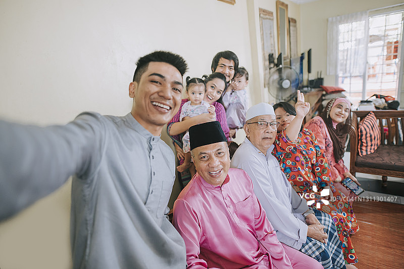 马来西亚一家人在家里庆祝开斋节，一边看着相机一边自拍图片素材