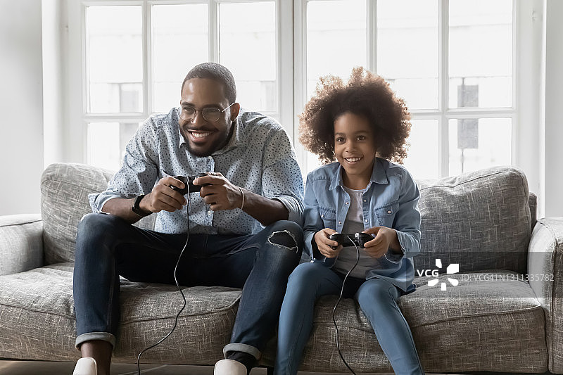 兴奋的女孩和她爸爸一起玩电子游戏图片素材