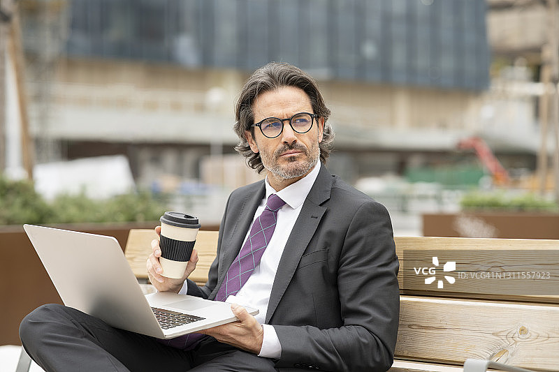 想象一个商人在长凳上拿着笔记本电脑喝咖啡图片素材