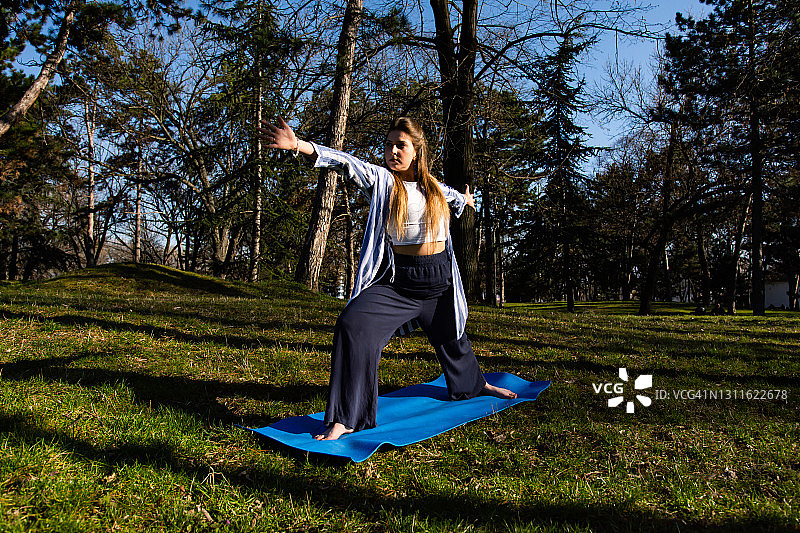 一个年轻漂亮的女人在公园里练瑜伽图片素材