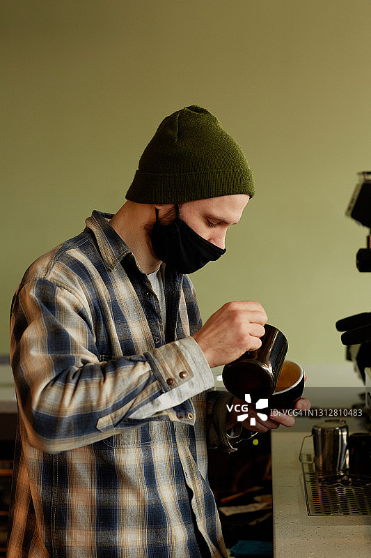 咖啡店侧视图中的咖啡师华林面具图片素材