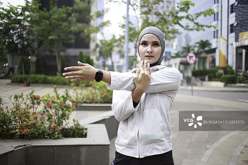 年轻的亚洲妇女希贾布伸展穿着运动服图片素材