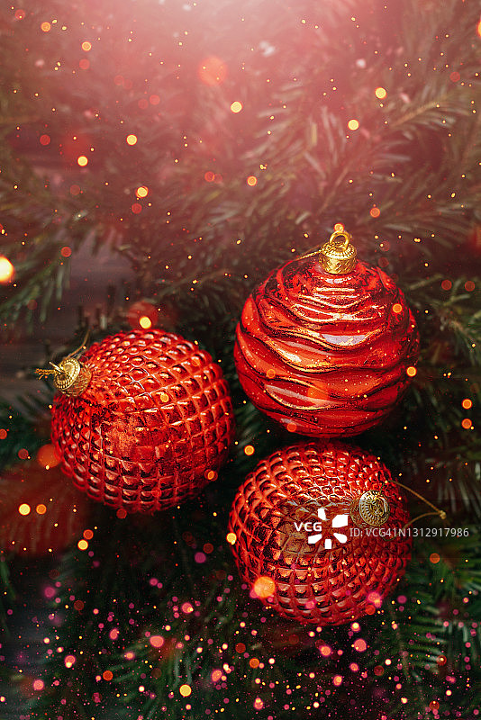 圣诞或新年贺卡上的红色小玩意在圣诞树的树枝上木制的桌子上模糊的金色灯光的背景。图片素材