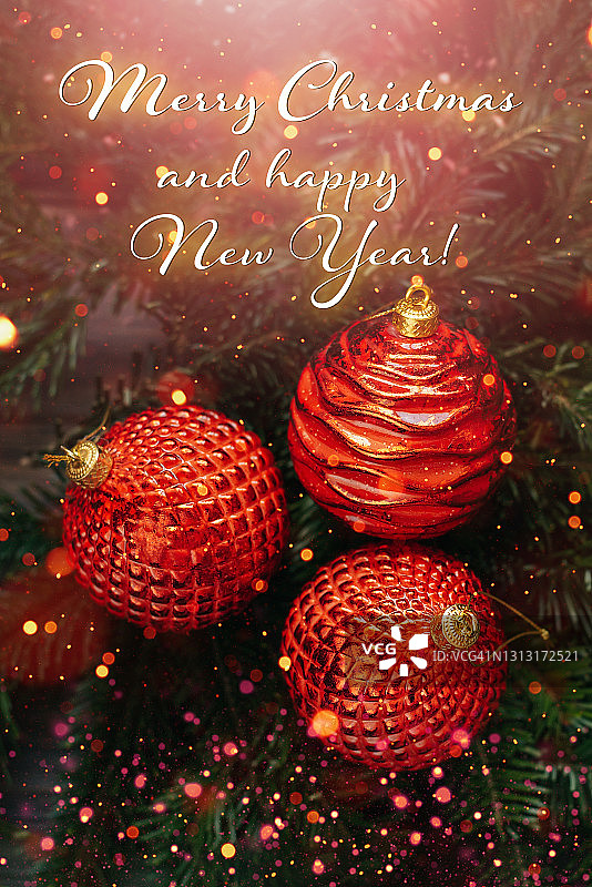 圣诞或新年贺卡上的红色小玩意在圣诞树的树枝上木制的桌子上模糊的金色灯光的背景。图片素材