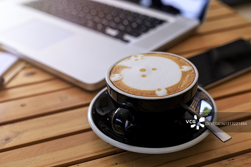 顶视图热咖啡杯模糊笔记本电脑智能手机和笔记本在木桌上。有智能手机、笔记本电脑和咖啡杯的办公桌。经营理念。复古风格的工艺图片素材