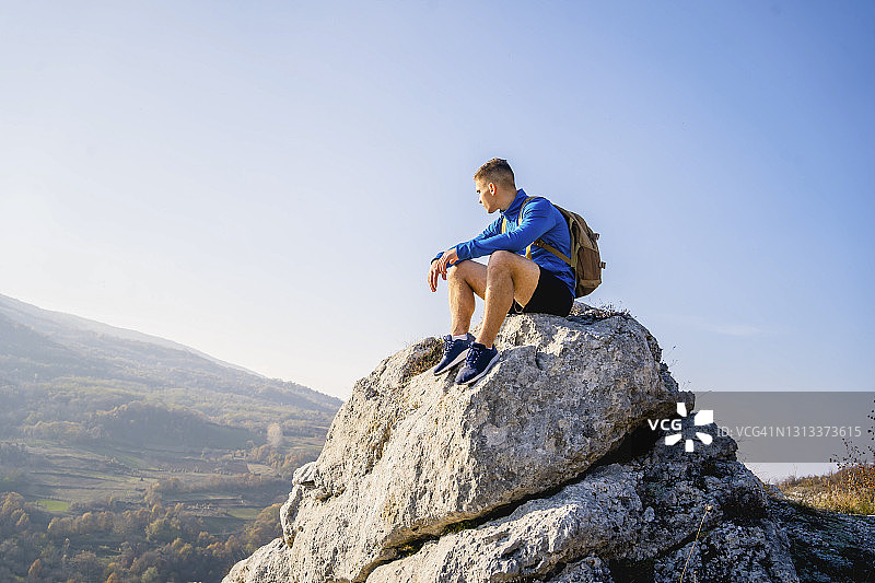 一个人坐在山顶上看风景图片素材