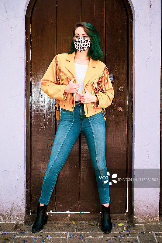 墨西哥城，一名年轻女子戴着口罩站在门框上看着摄像机图片素材