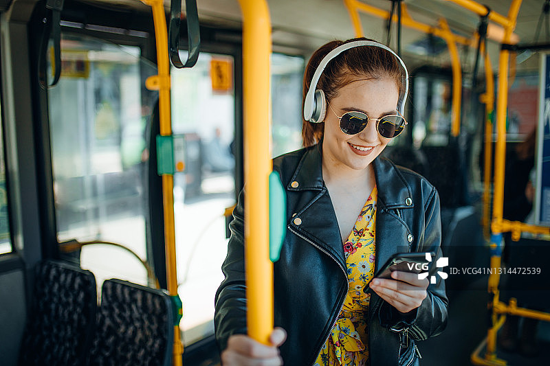 一名年轻女子在公交车上一边发短信一边听音乐图片素材
