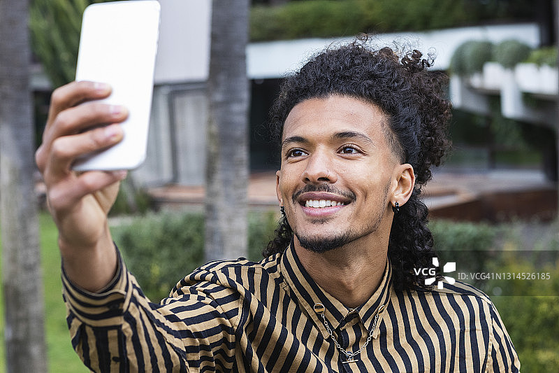 微笑的男人用智能手机自拍图片素材