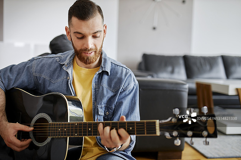 一张英俊的年轻人在家弹吉他的照片图片素材