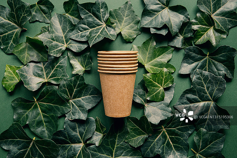 环保工艺纸杯在绿色背景与常青藤叶子。回收的概念。“零浪费”的主题。俯视图图片素材