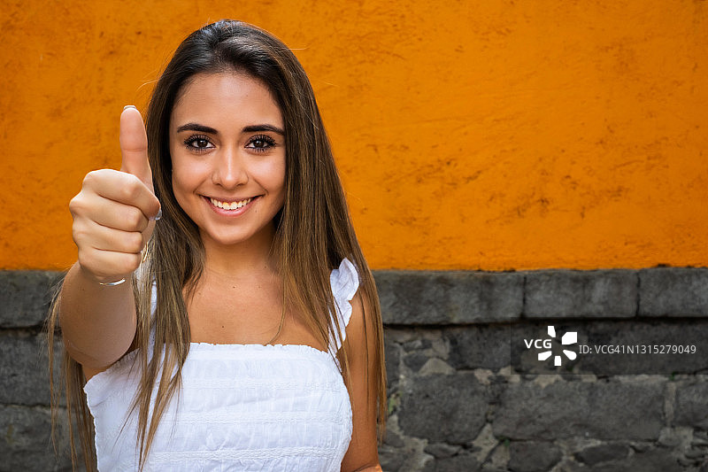 在墨西哥城，年轻的西班牙妇女看着镜头，竖起大拇指图片素材
