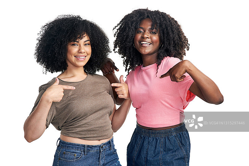 摄影棚拍摄了两名年轻女子在白色背景下指着自己的t恤图片素材