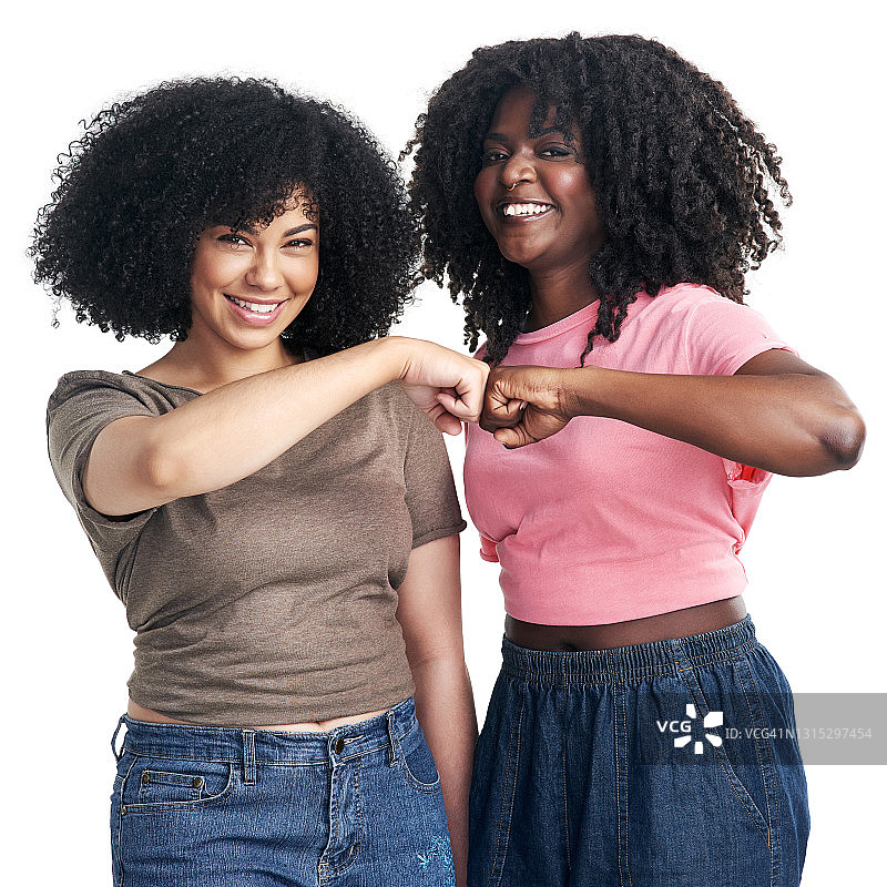 摄影棚拍摄了两个年轻女子用拳头撞在白色背景上的画面图片素材