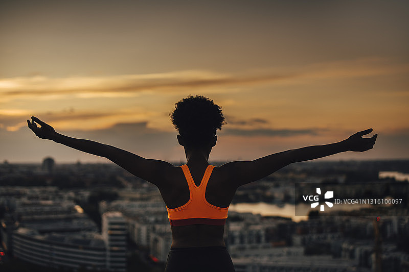 在日落时伸开双臂锻炼的女运动员图片素材
