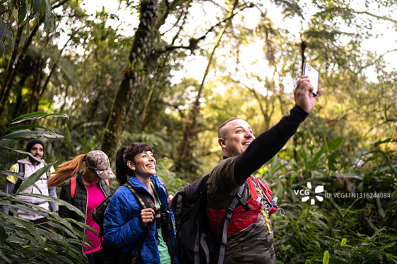 一群人在森林徒步旅行时用智能手机拍摄图片素材