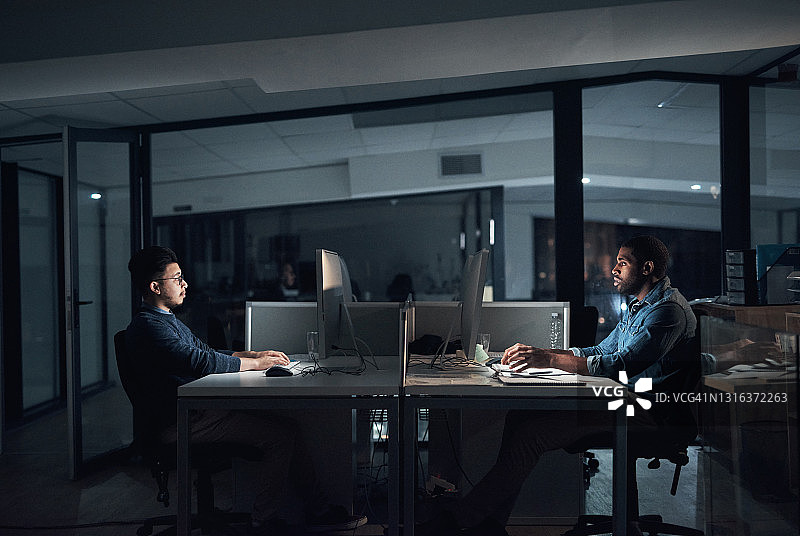 年轻的商人在深夜在现代的办公室里使用他们的电脑图片素材