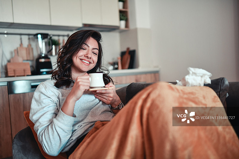 微笑的女性在床上喝咖啡，轻松度过COVID-19图片素材