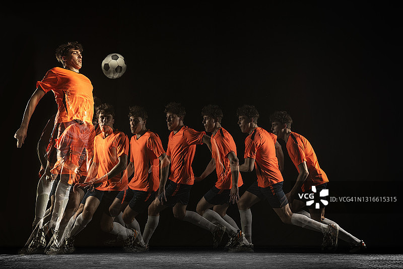 白人年轻男子足球运动员在运动和行动在混合光在黑暗的背景。图片素材