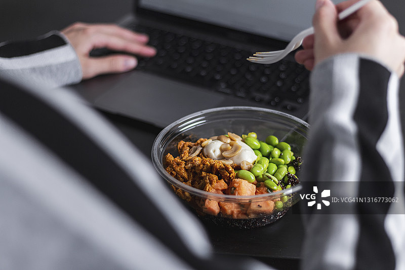 特写一个人吃一个健康的午餐在一个塑料容器。午餐在工作。图片素材