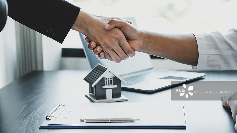 房地产经纪人和买家在签订商业合同、租赁、购买、抵押、贷款或房屋保险后握手图片素材