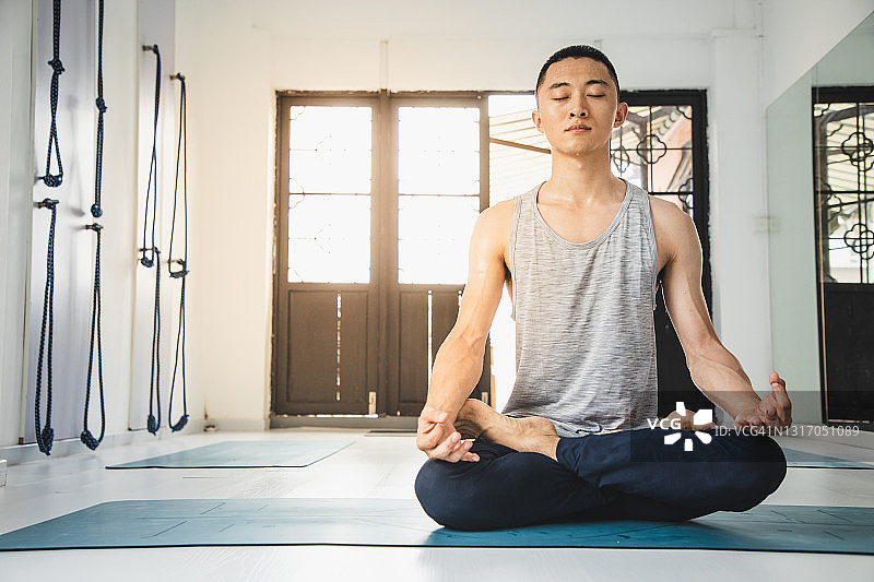 一个亚洲人在瑜伽房里冥想图片素材