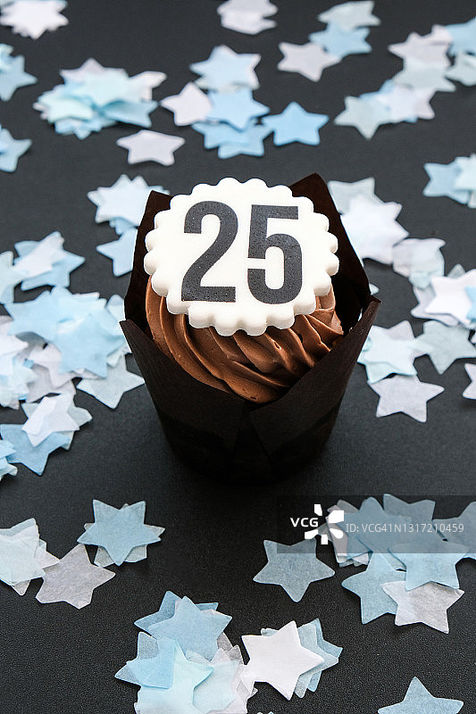 美味巧克力小蛋糕25号，黑色背景上有奶油。松饼。生日蛋糕。25周年纪念图片素材