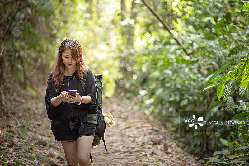 亚洲华人中年女性旅行徒步使用移动指南针在森林背包图片素材