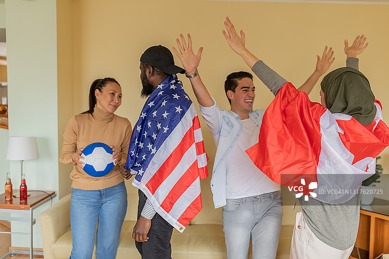 一群来自美国和加拿大的年轻朋友在现代公寓享受一场足球比赛。图片素材