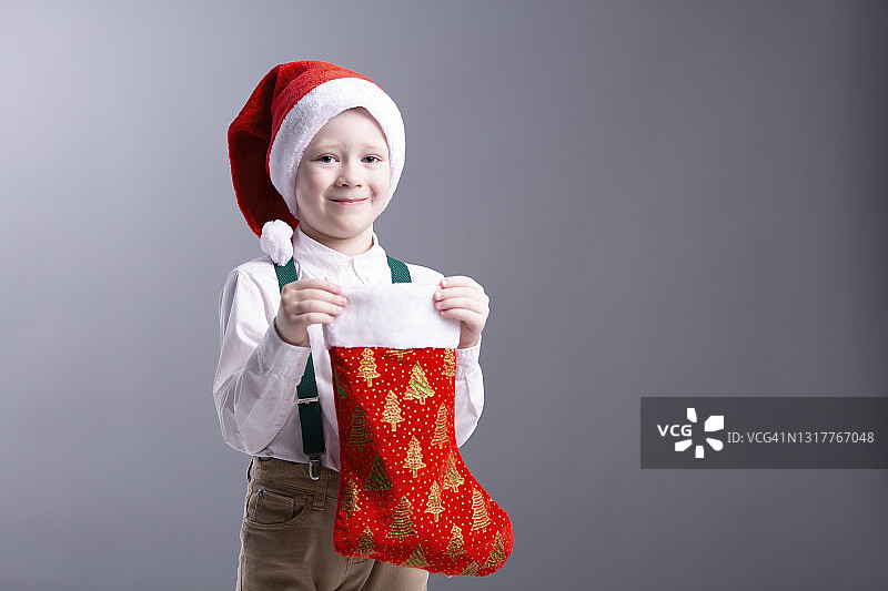 美丽可爱的男孩站着，微笑着，拿着圣诞礼物图片素材