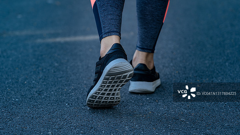 近距离的跑鞋和腿女人走在街上。女运动员在户外慢跑和训练。健康的生活方式图片素材
