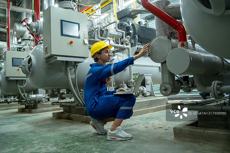 在工业锅炉控制室工作的女电气工程师。图片素材