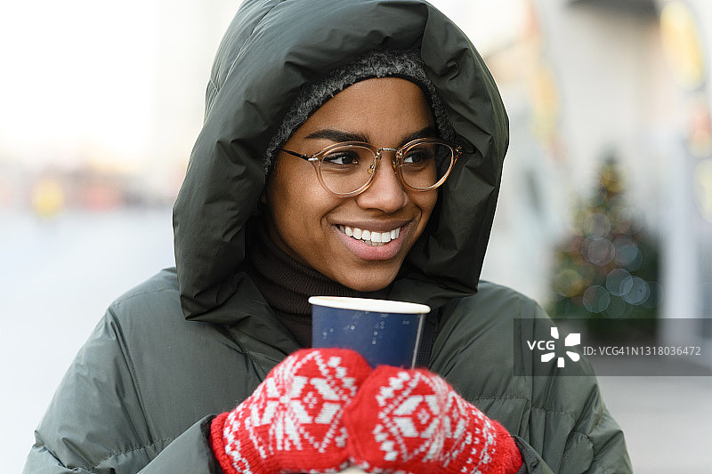 微笑的女人与可重复使用的杯子戴手套在冬天图片素材