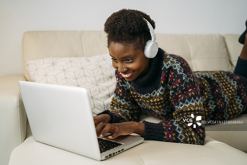 面带微笑的女企业家戴着耳机在起居室用笔记本电脑工作图片素材