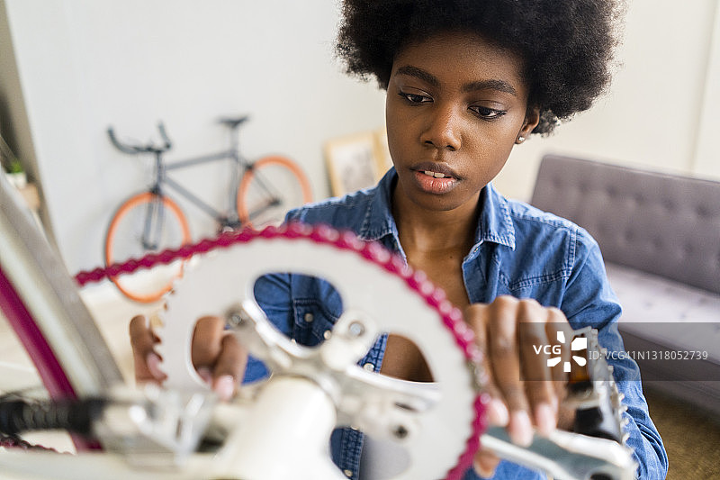 非洲发型的女人在家里修理自行车链图片素材