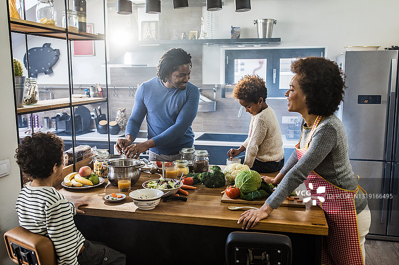 快乐的黑人家庭在厨房做饭。图片素材
