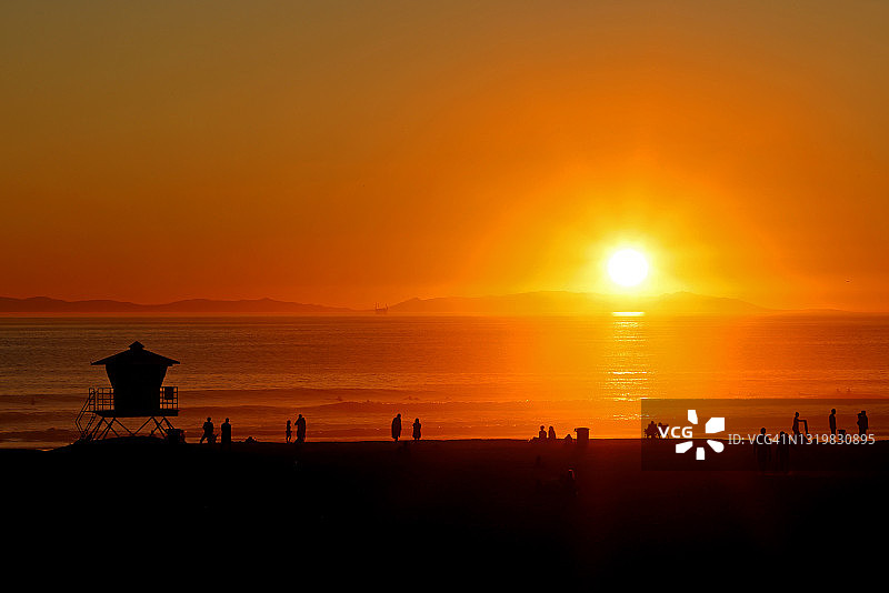 人们在加州亨廷顿海滩的海滩上欣赏日落图片素材