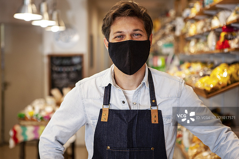 年轻企业家戴着防护口罩站在健康食品店内的肖像图片素材